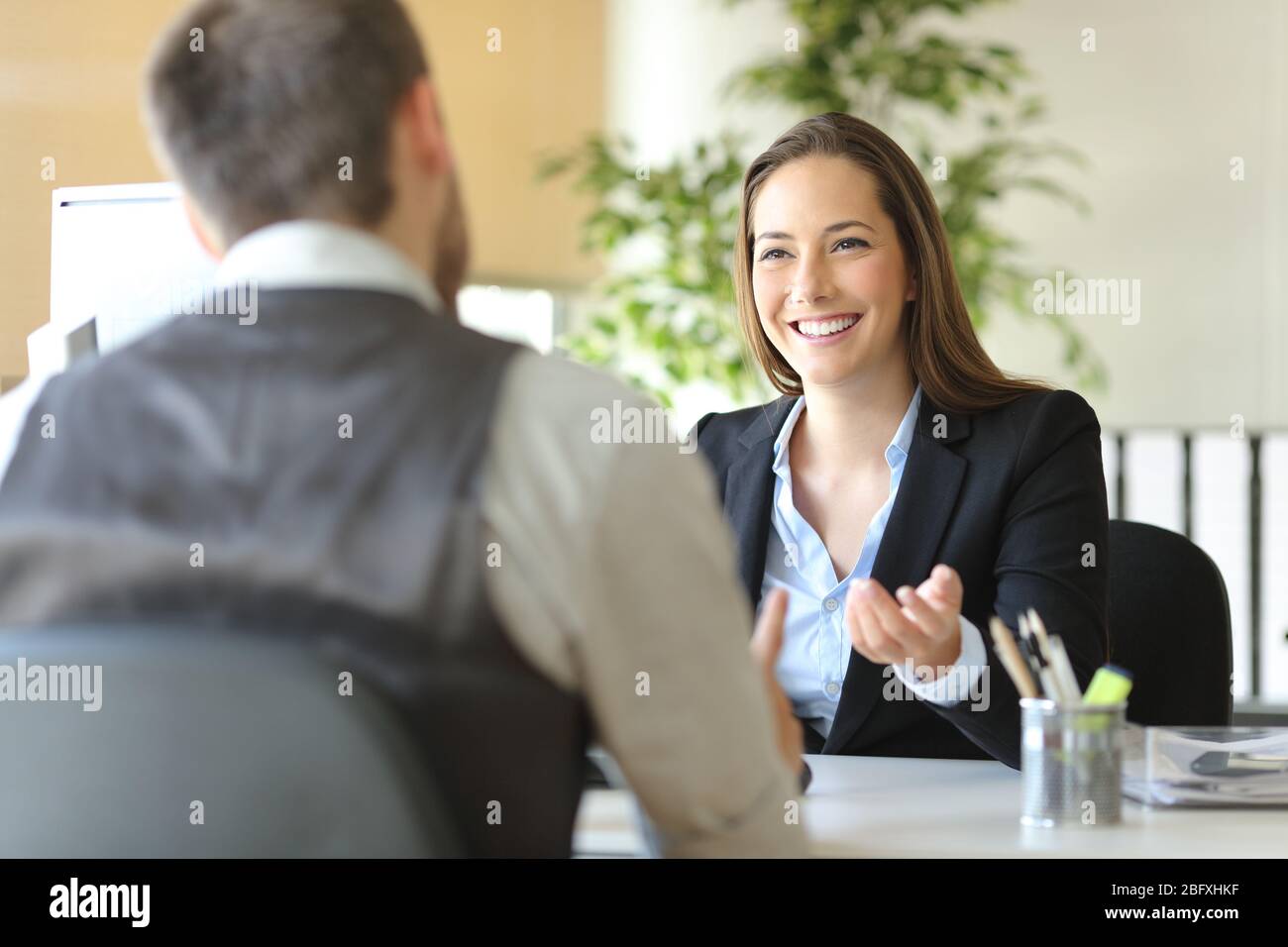 Glückliche Executive-Mitarbeiter lachen und reden auf einem Schreibtisch im Büro Stockfoto