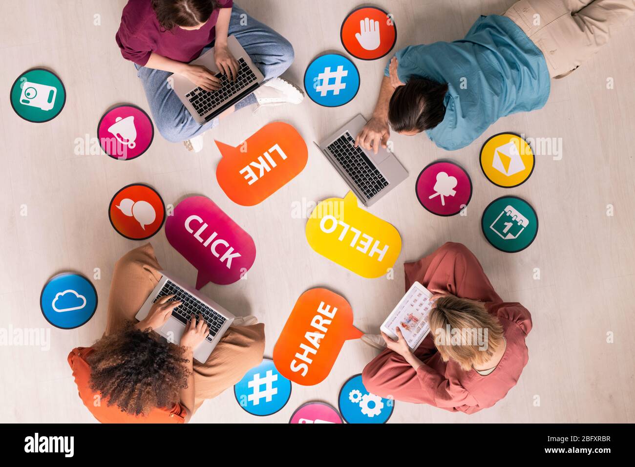 Ansicht von Internetnutzern, die im Kreis zwischen Social Media Activity Tags und Icons sitzen und auf Geräten im Netz surfen Stockfoto