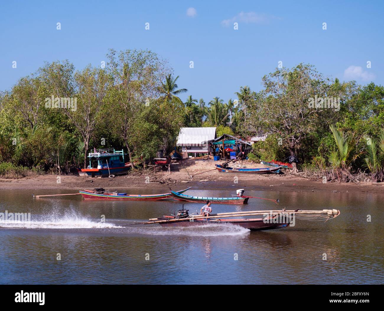 Kleines Langschwanz-Fischerboot auf Mak Bang, Satun City, Satun im Süden Thailands. Bootsbau Werkstatt im Hintergrund. Stockfoto