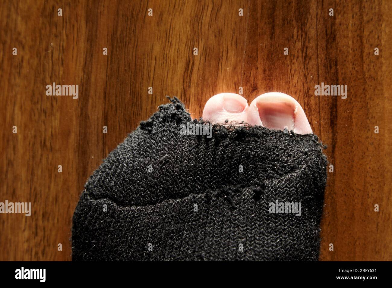 mans Zehen stocken aus dem Loch in schwarzen Socken Stockfoto