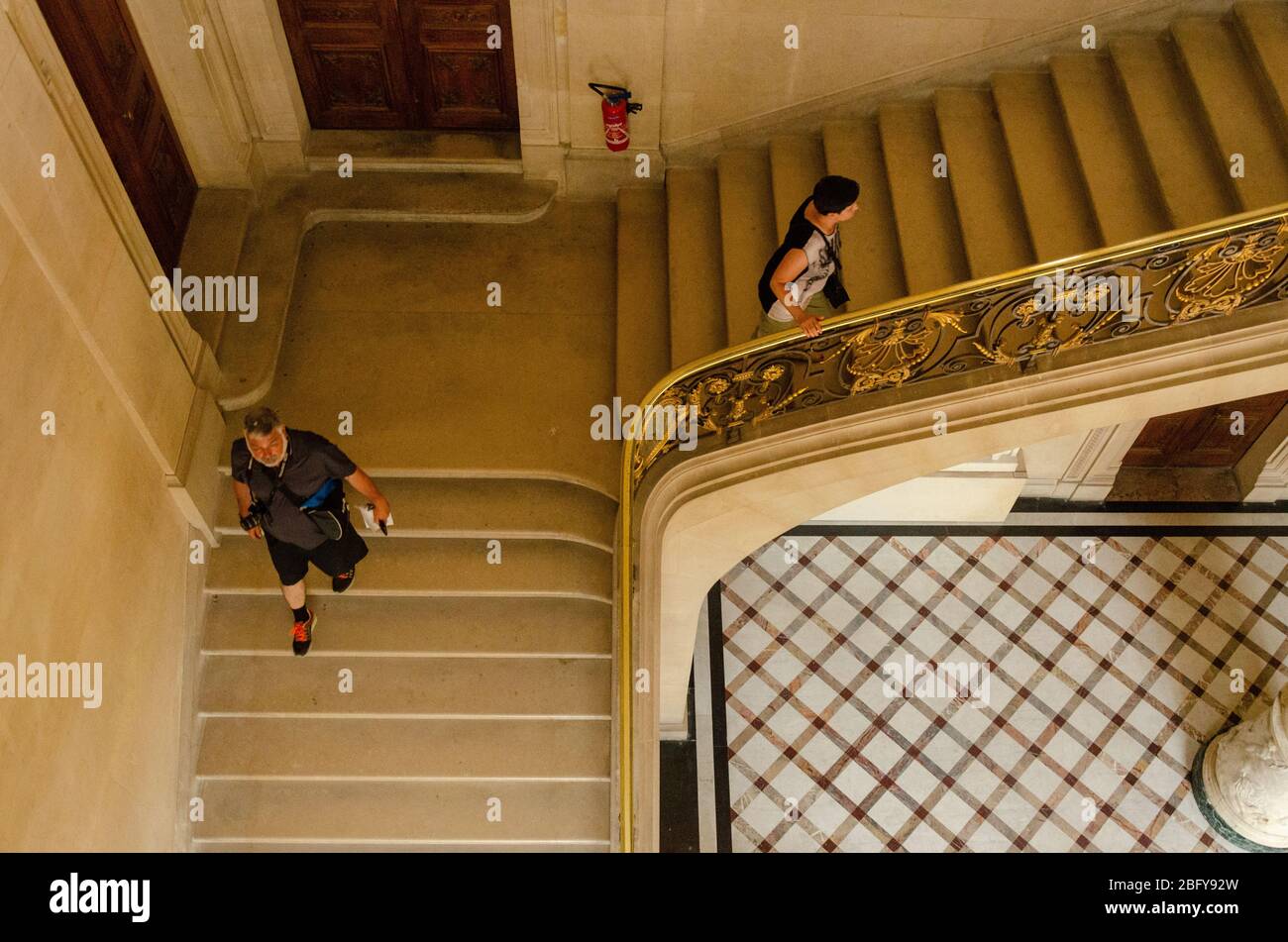 Draufsicht eines Mannes und einer Frau, die in 90 Grad entgegengesetzte Richtungen auf einer Treppe im Louvre, Paris, Frankreich, gehen Stockfoto