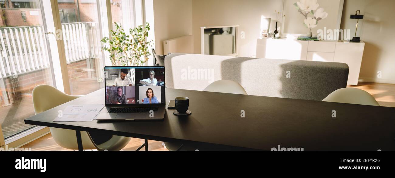 Laptop auf dem Tisch mit einem Videoanruf auf dem Bildschirm im Wohnzimmer. Menschen, die VoIP nutzen, um sich miteinander zu verbinden. Stockfoto