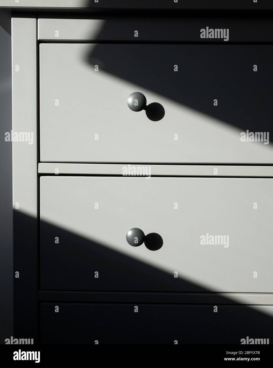 Sonnenlicht wirft Schatten auf eine graue Reihe von Schlafzimmer Lagerung zieht. Stockfoto