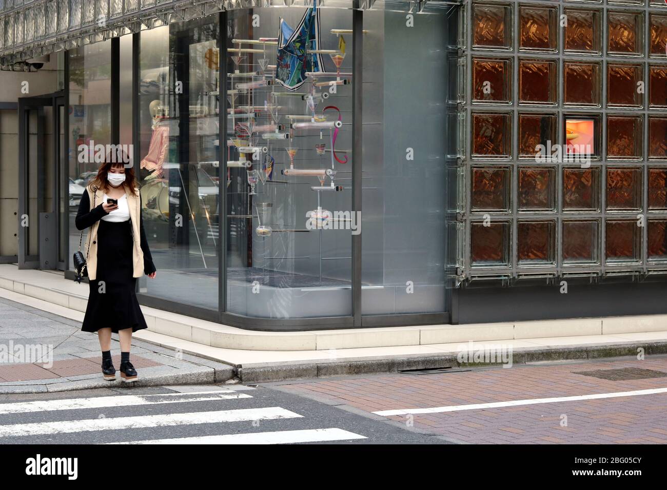 Eine Fußgänger-Maske in einer ungewöhnlich ruhigen Straße von Ginza Maison Hermes. Aufgrund des Coronavirus-Ausbruchs sind die Geschäfte im April 2020 geschlossen. Stockfoto