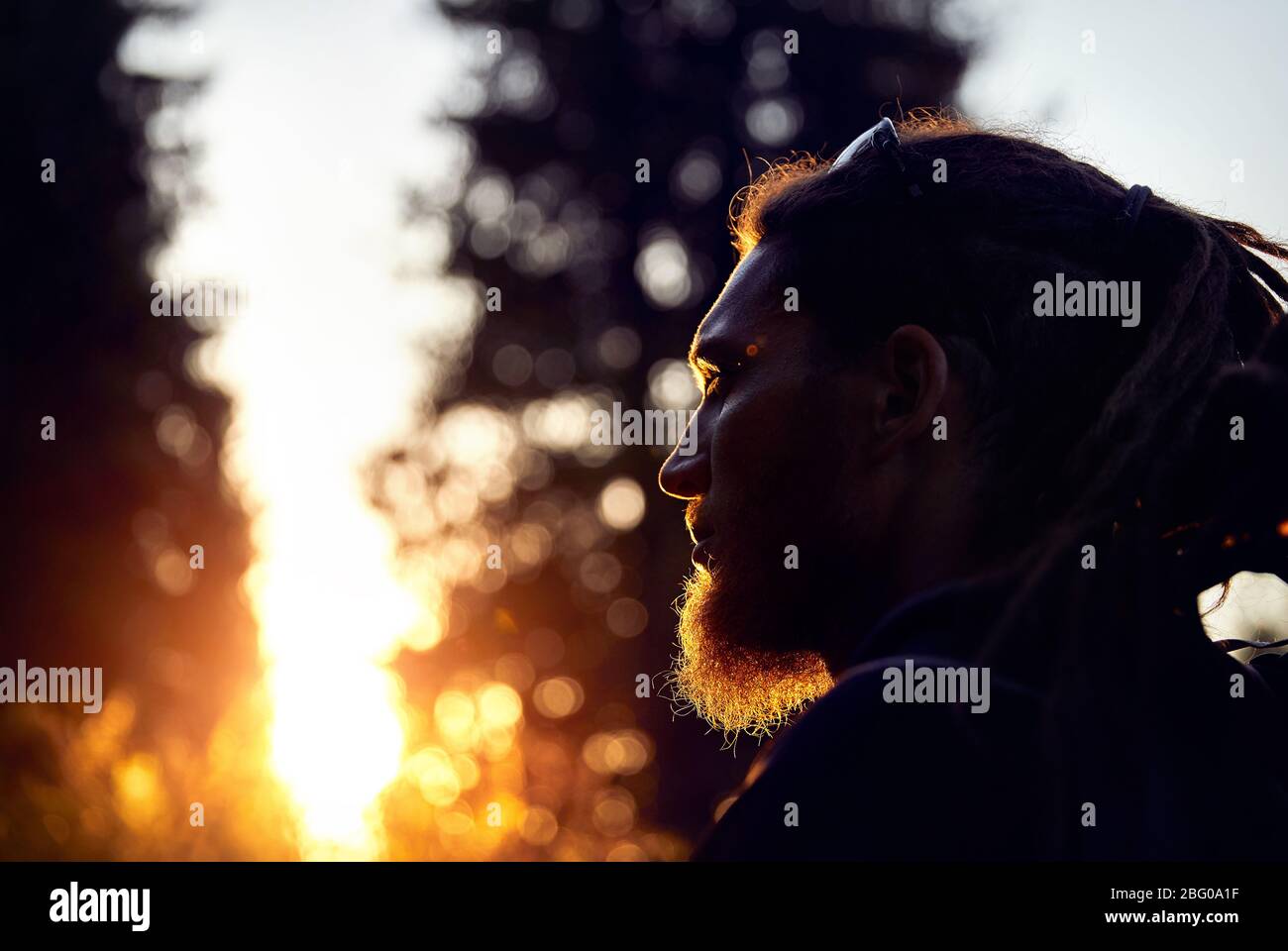 Mann Silhouette mit Dreadlocks in Sunset Mountain Forest Stockfoto