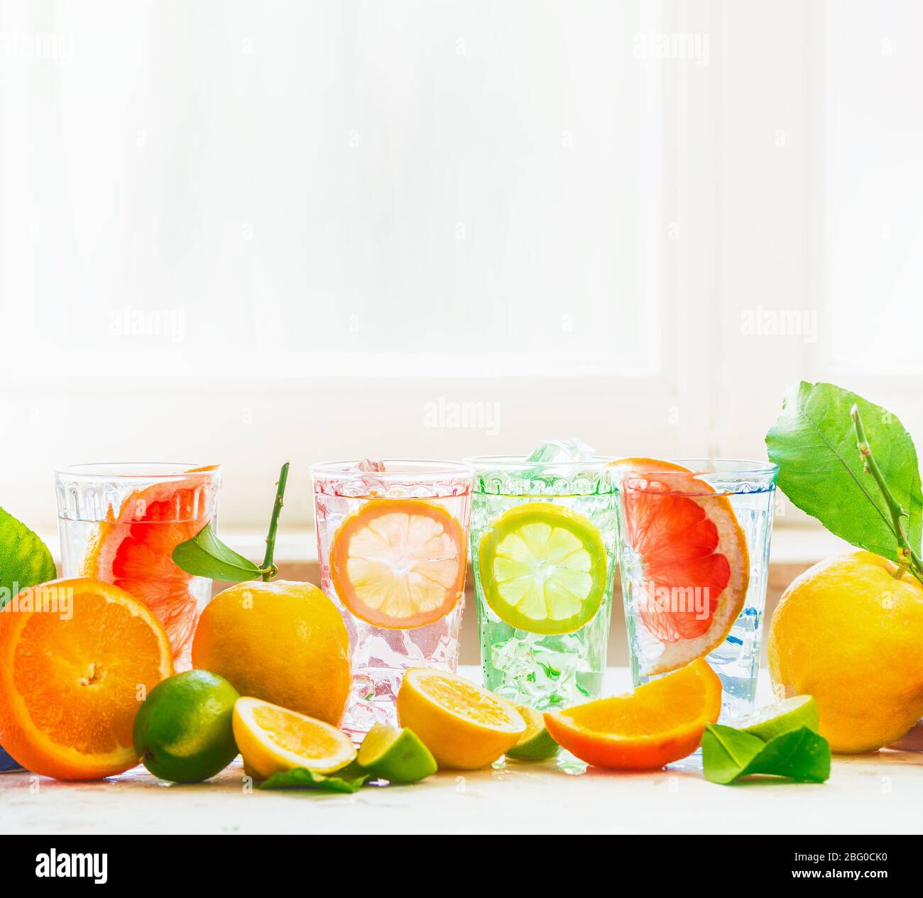 Sommerfrische Getränke Party im Sonnenlicht auf weißem Tisch mit verschiedenen Zitrusfrüchten: Zitrone, Orange, Limette und Grapefruit auf hellen Fensterhintergrund. H Stockfoto