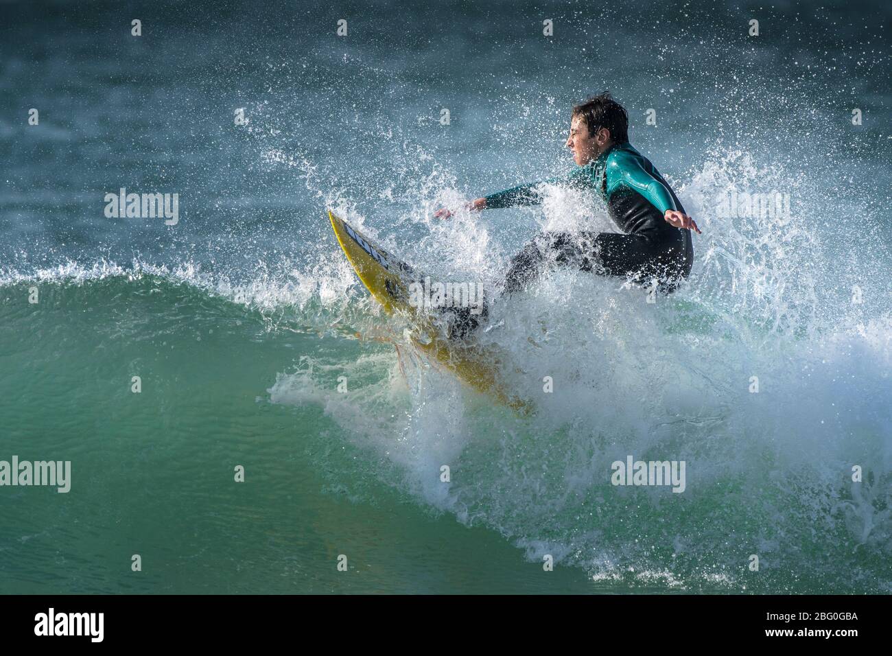 Spektakuläre Surferaction, während ein junger Surfer eine Welle im Fistral in Newquay in Cornwall reitet. Stockfoto