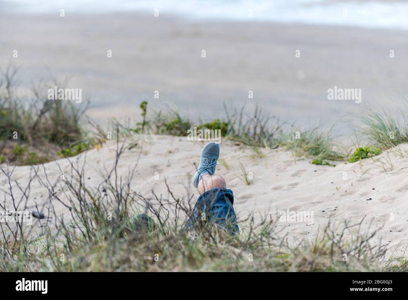 Der Fuß eines Mannes, der sich im Sanddünensystem bei Fistral in Newquay in Cornwall entspannt. Stockfoto
