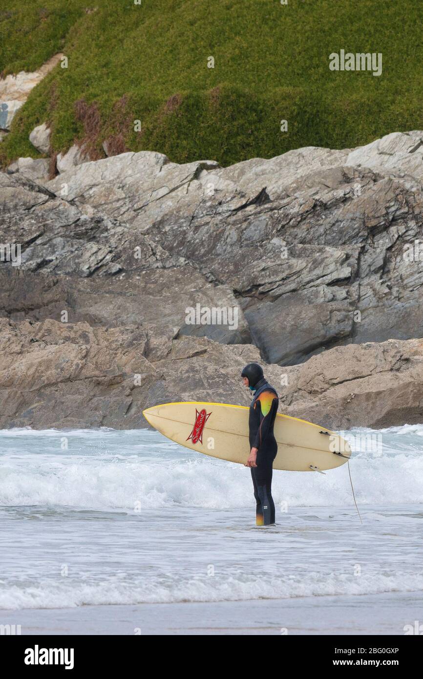 Ein Surfer steht am Fistral Beach in Newquay in Cornwall und hält sein Surfbrett und ist in Gedanken verloren. Stockfoto