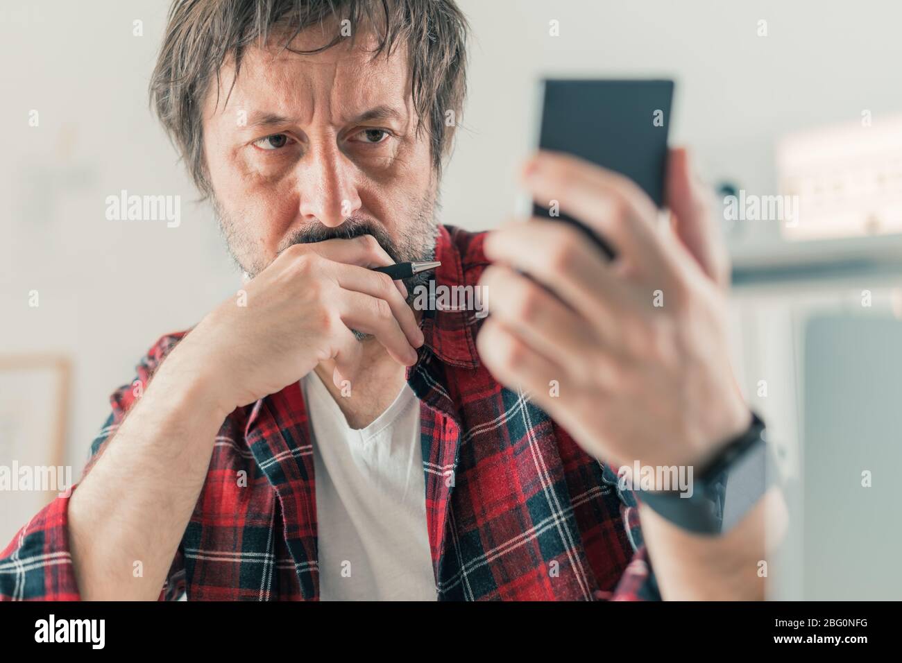 Besorgt Freiberufler Lesen von SMS auf dem Mobiltelefon in seinem kleinen Unternehmen Home Office, selektive Fokus Stockfoto