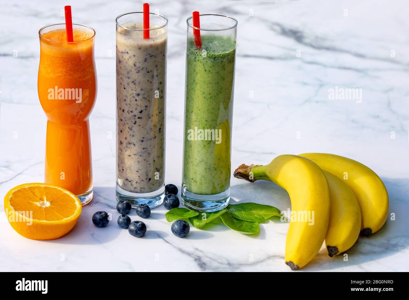 3 verschiedene Smoothies mit Zutaten auf Marmortisch Hintergrund Stockfoto