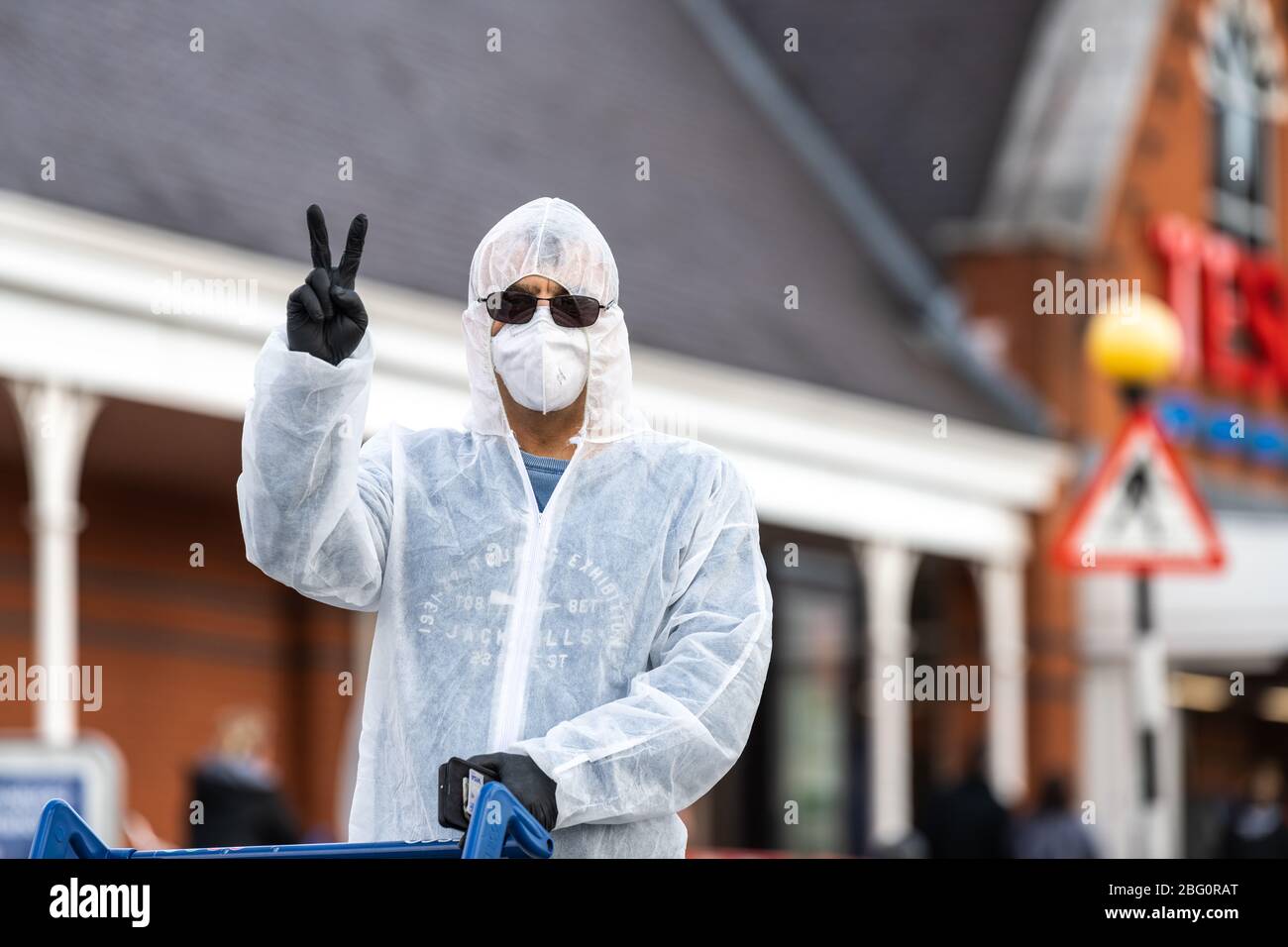 Shopper trägt einen vollen Hasmatanzug und Maske im Cheltenham Tesco Superstore während der Coronavirus-Pandemie. Stockfoto