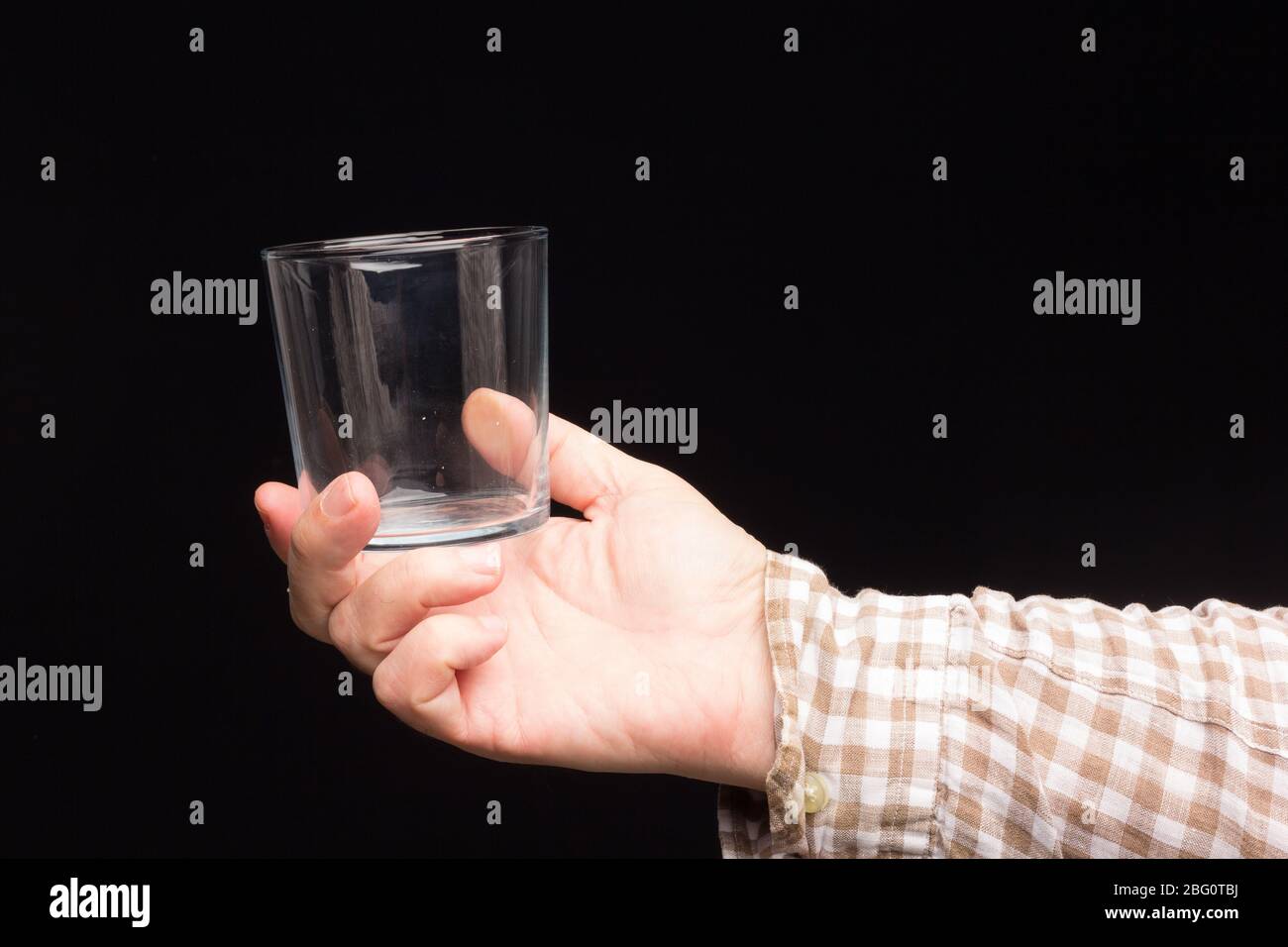 Transparente Glasschale in der Hand einer Person. Glas mit Wasser oder transparenter Flüssigkeit gefüllt. Trinkwasser Stockfoto