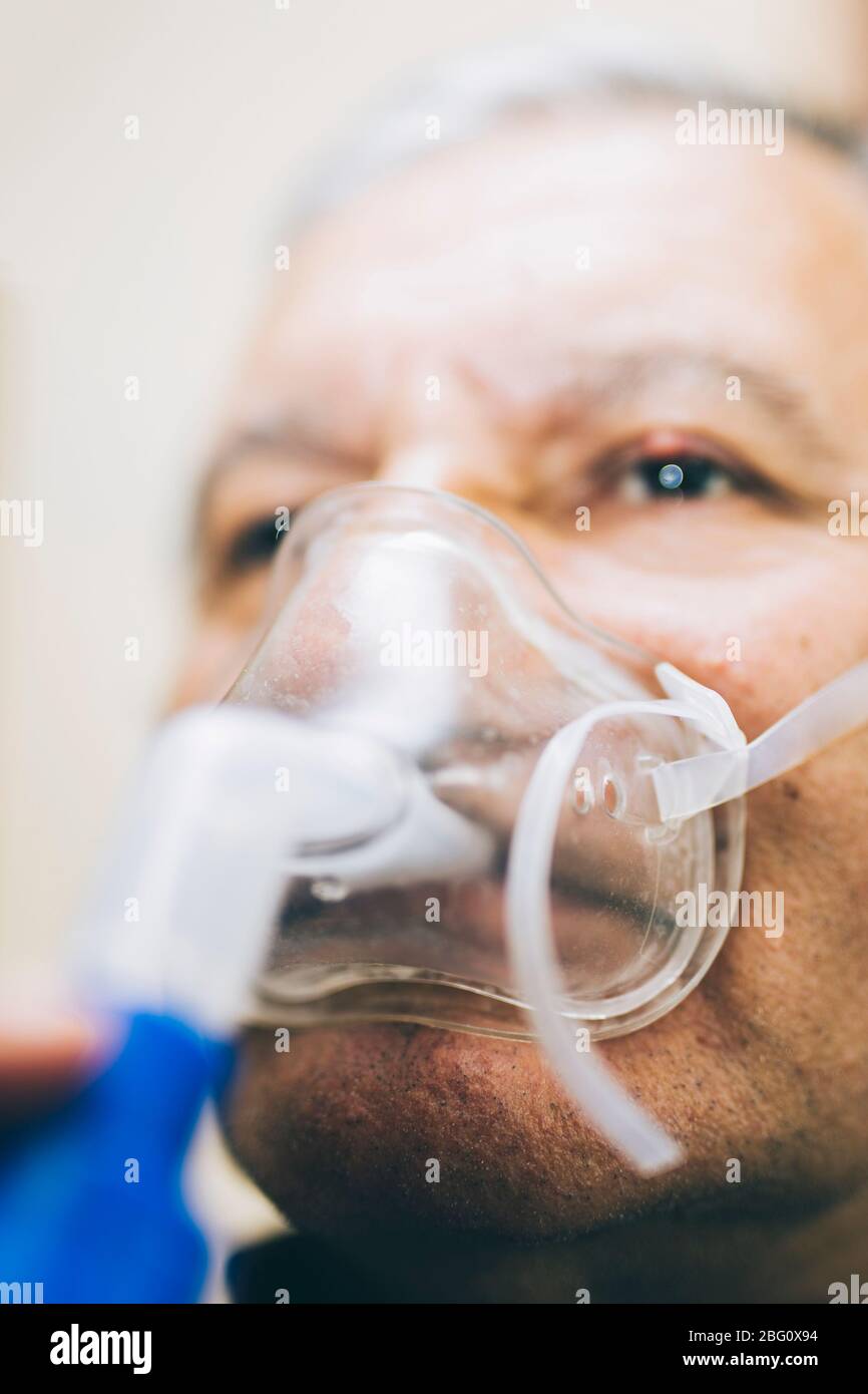Leitender Mann, der medizinische Geräte für die Inhalation mit Atemschutzmaske verwendet, Vernebler im Zimmer Stockfoto