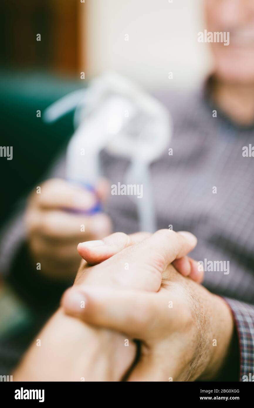 Leitender Mann, der medizinische Geräte für die Inhalation mit Atemschutzmaske verwendet, Vernebler im Zimmer Stockfoto