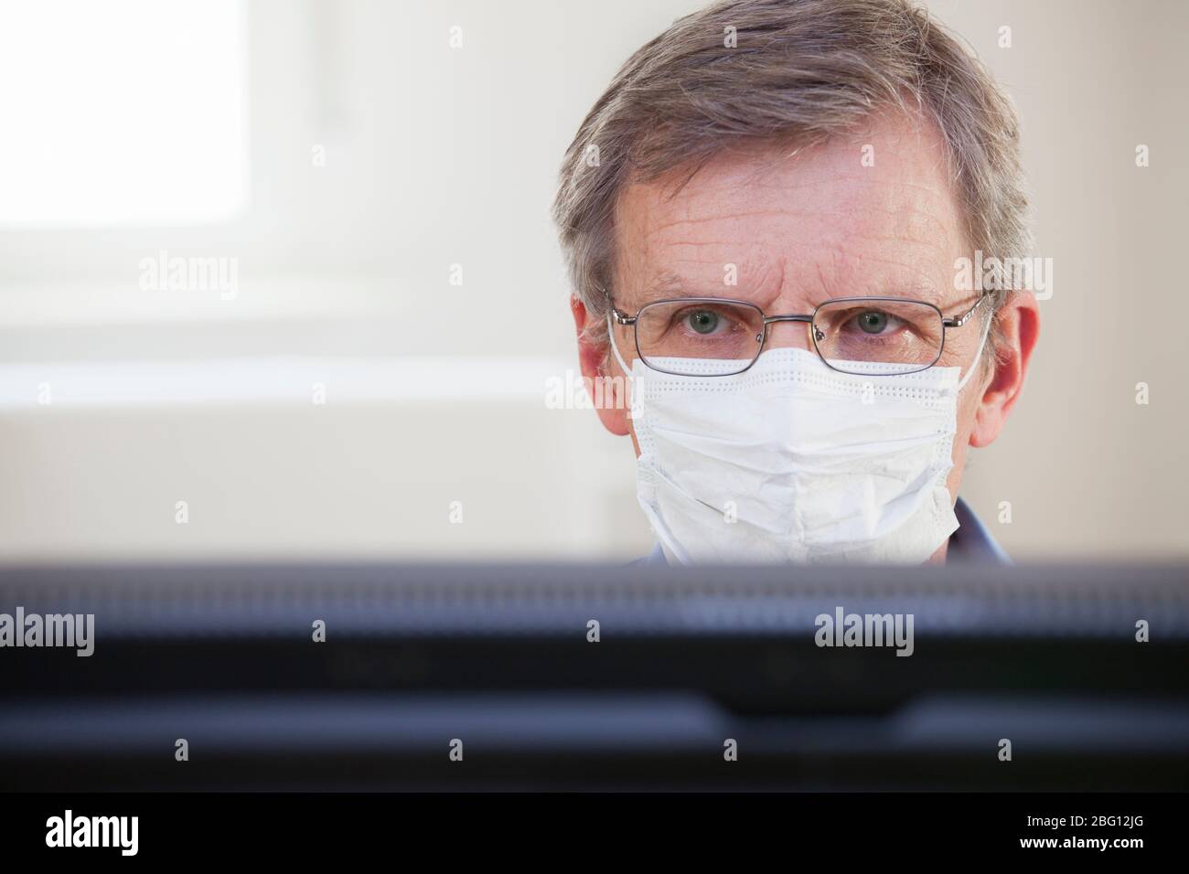 Konzentrierter Arzt oder Geschäftsmann, der die Zahlen auf einem Computermonitor in einem Krankenhaus oder Büro ansieht - selektiver Fokus Stockfoto