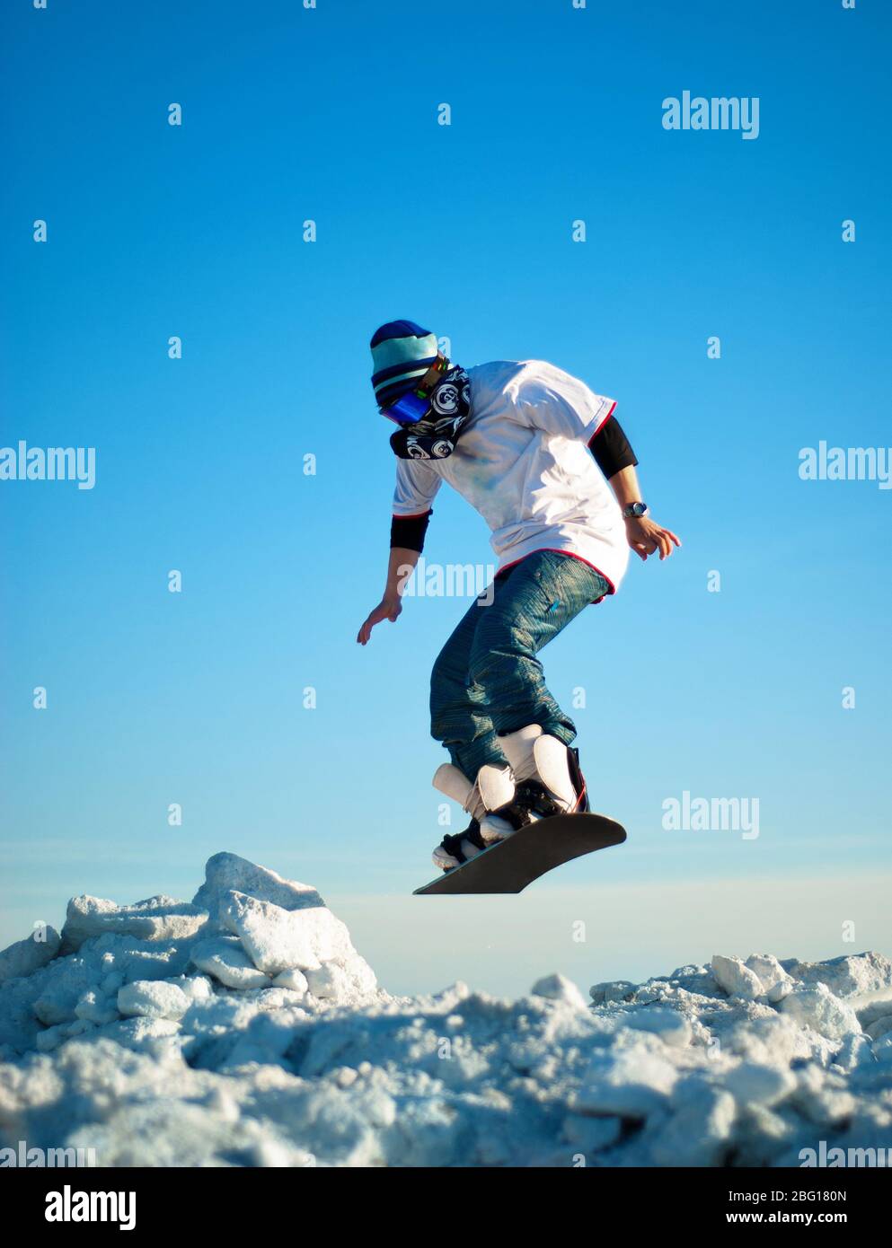 Snowboarder, die gegen den klaren blauen Himmel springen Stockfoto