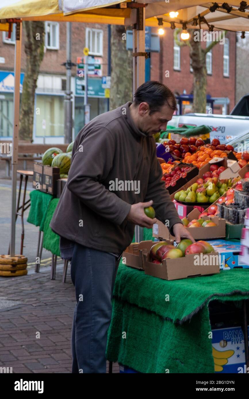 Ein Lebensmittelhändler, der auf seinem Obst- und Gemüsestall oder Marktstand Vorrat legt Stockfoto