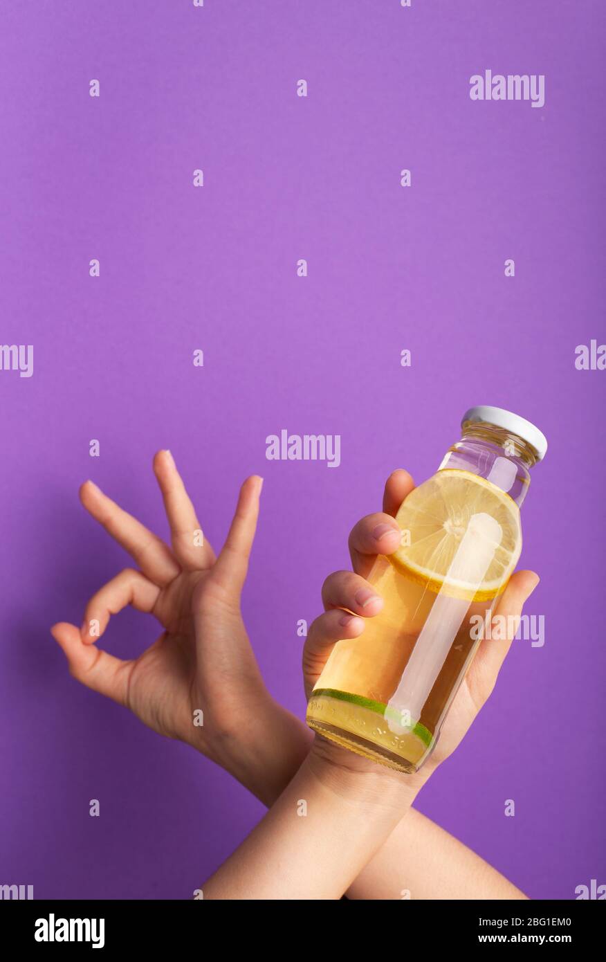 Frau zeigt ok und eine Flasche Detox Wasser mit aufgeschnittenen rohen Zitrone infundiert Stockfoto