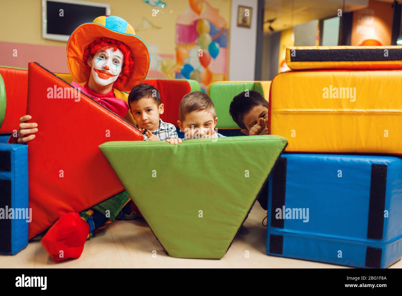 Clown und kleine Jungen versteckten sich hinter den weichen Blöcken Stockfoto