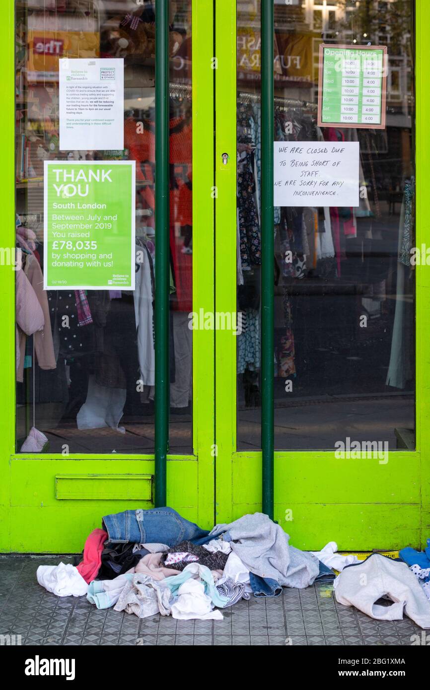 Während der Londoner Schließung, die aufgrund der Verbreitung von Covid-19, 19. April 2020, stattfand, stapelten sich die Kleidungsstücke vor dem geschlossenen Barnardo's Charity Shop in Brixton Stockfoto