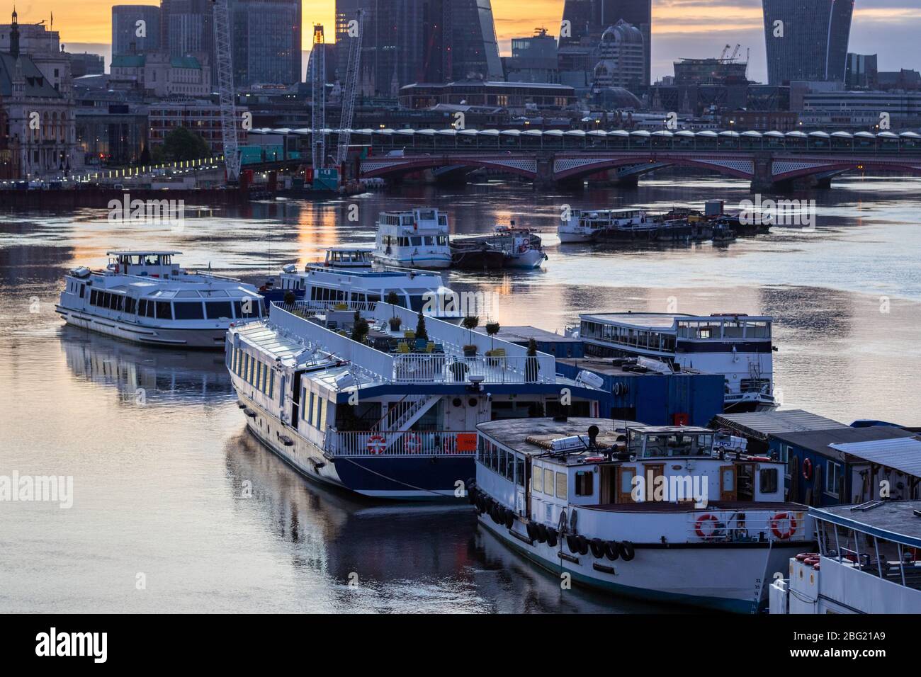 Am frühen Morgen werden leichte Vergnügungsboote auf der Themse mit Blackfriars Bridge im Hintergrund vertäut. Von der Waterloo Bridge Stockfoto