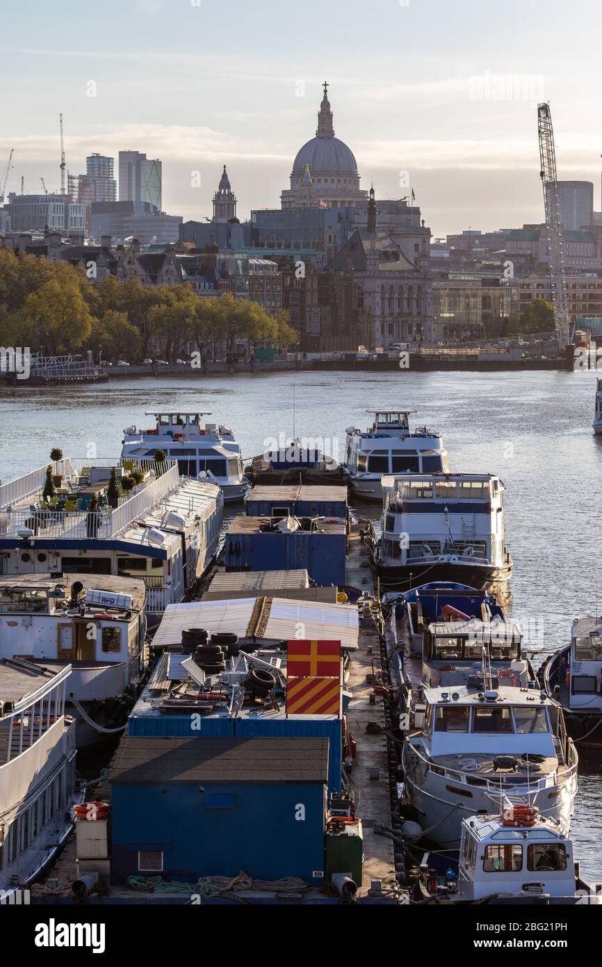 Am frühen Morgen werden leichte Vergnügungsboote auf der Themse mit dem Dome of St Paul's im Hintergrund vertäut. Von der Waterloo Bridge Stockfoto