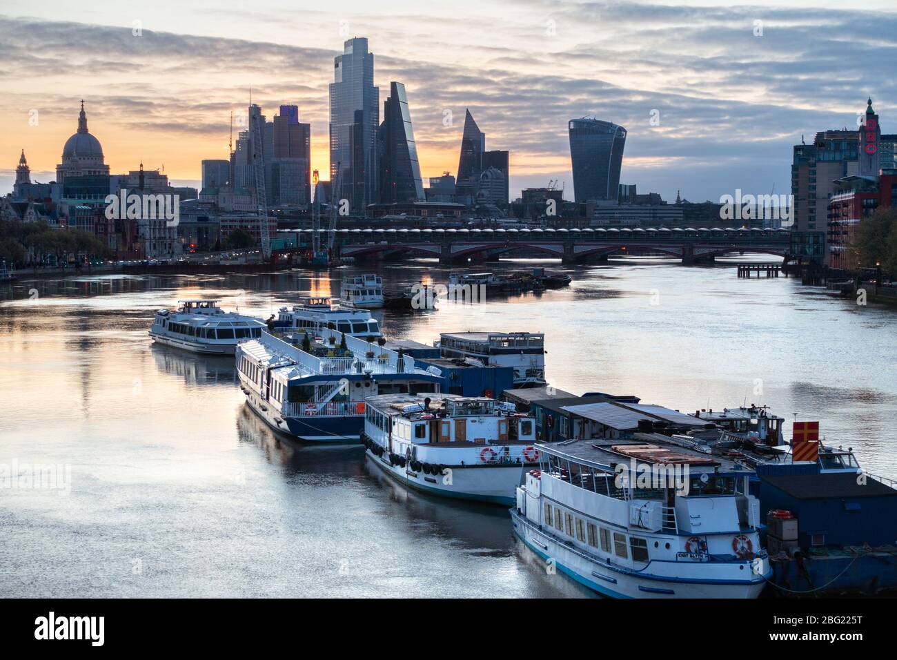 Am frühen Morgen werden leichte Vergnügungsboote auf der Themse mit St Paul's und der City of London im Hintergrund vertäut. Von der Waterloo Bridge Stockfoto