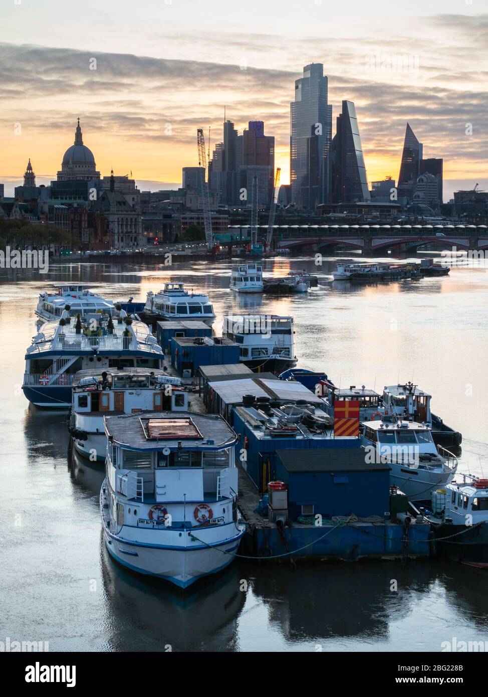 Am frühen Morgen werden leichte Vergnügungsboote auf der Themse mit St Paul's und der City of London im Hintergrund vertäut. Von der Waterloo Bridge Stockfoto