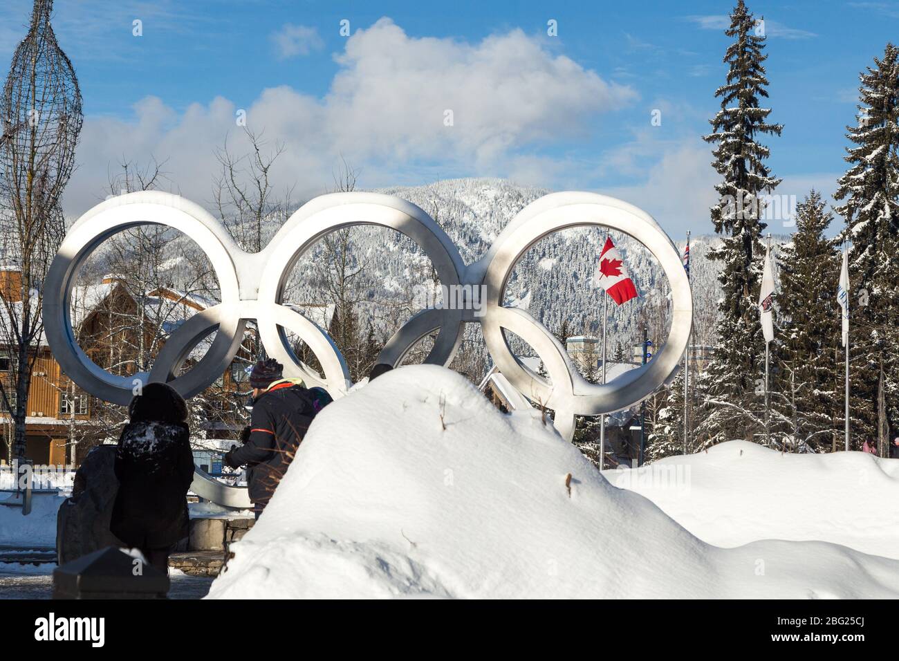 WHISTLER, BC, KANADA - 17. JANUAR 2020: Die olympischen Ringe in Whistler Village mit Touristen, die Fotos machen und die kanadische Flagge. Stockfoto