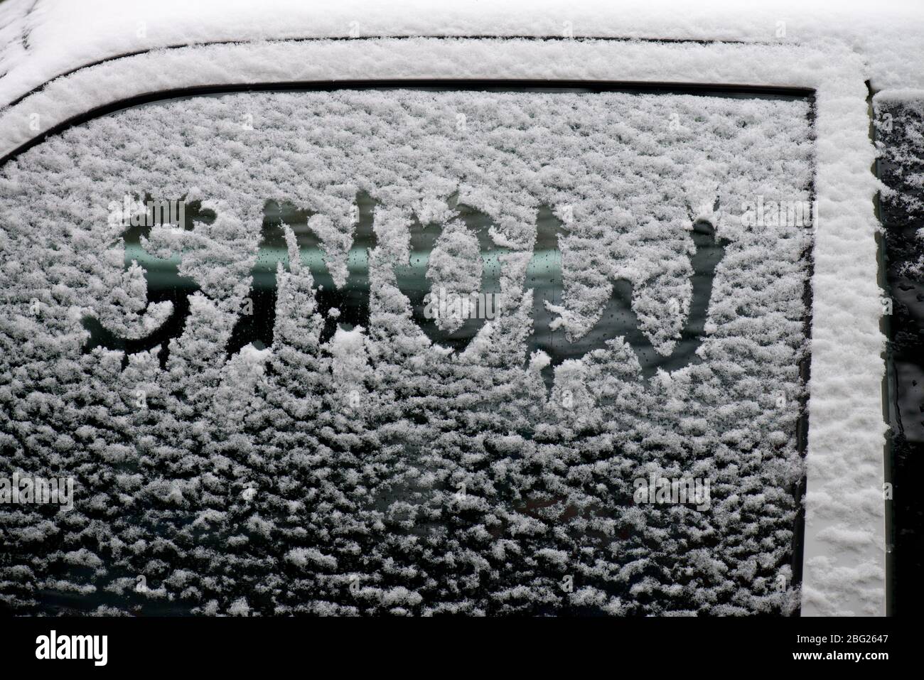 Ein Autofenster mit Schneestauben bedeckt mit dem Wort Schnee darin geschrieben Stockfoto