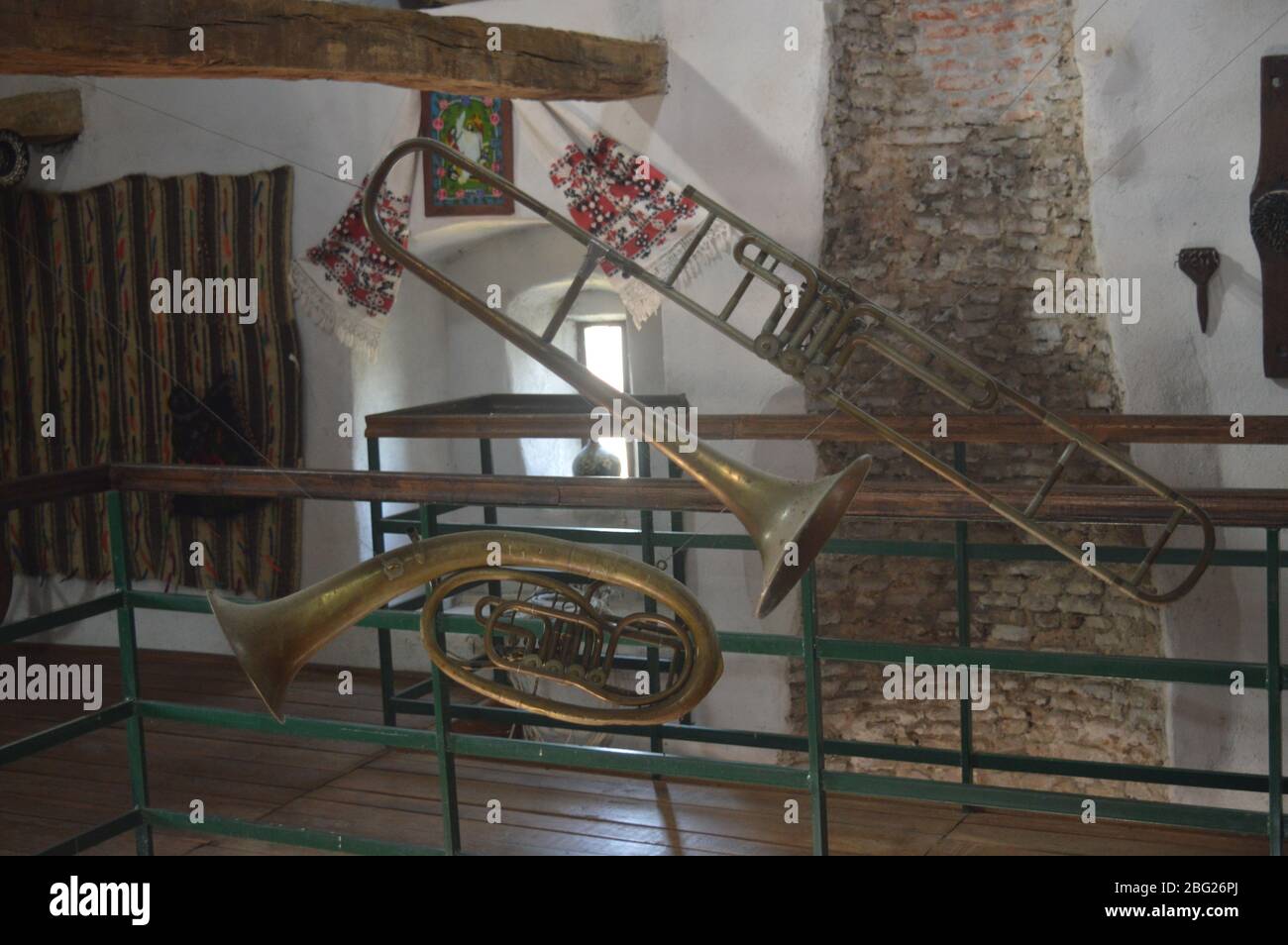 Alte Messingblasinstrumente, darunter eine alte Posaune und ein Horn, werden in einem historischen rumänischen Museumsturm mit rustikalen Steinmauern ausgestellt. Stockfoto