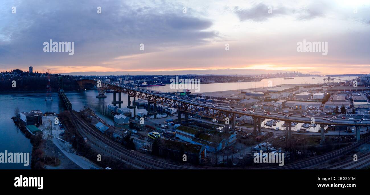 Luftdrohne-Aufnahme des Pendlerverkehrs auf der zweiten Narrows-Brücke und den Industriehafen in Vancouver, BC, Kanada bei Sonnenuntergang. Stockfoto