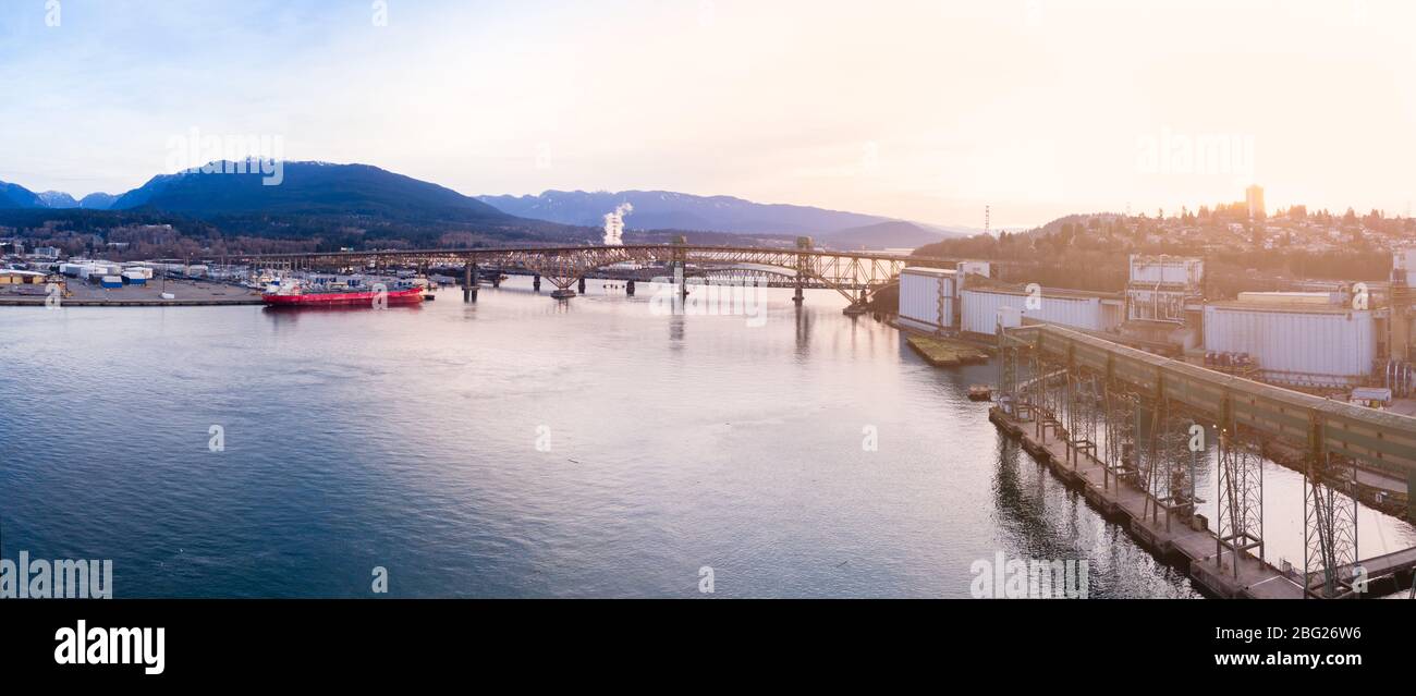 Luftdrohne-Aufnahme des Pendlerverkehrs auf der zweiten Narrows-Brücke und den Industriehafen in Vancouver, BC, Kanada bei Sonnenaufgang. Stockfoto