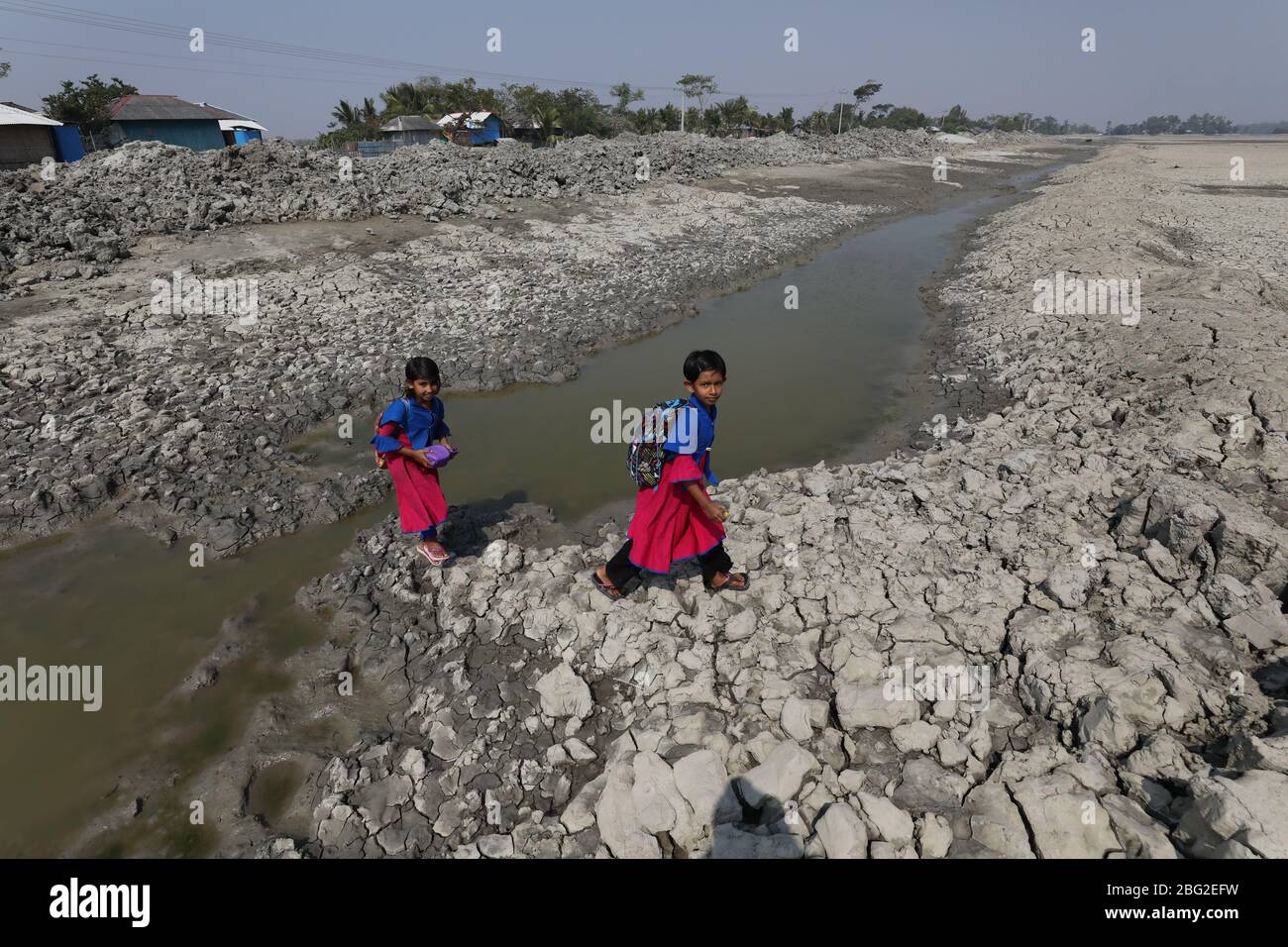 Khulna, Bangladesch: Schulmädchen gehen nach der besuchten Schule am Rande des Sundarbans Mangrovenwaldes, dem Welterbe, in Bangladesch nach Hause. Das Leben der Menschen wird durch die Auswirkungen des Klimawandels jeden Tag schlechter. Die meisten Menschen sind für ihren Lebensunterhalt auf den Wald angewiesen. Die Wasserkrise ist eines der größten Probleme in ihrem Leben, da salzhales Wasser über die Küste in Bangladesch geht. Die meisten Menschen haben an die Flüsse gefischt, einige von ihnen sammeln Honig und Holz aus dem Mangrovenwald. In der Trockenzeit leiden die Menschen unter reinem Trinkwasser. Stockfoto