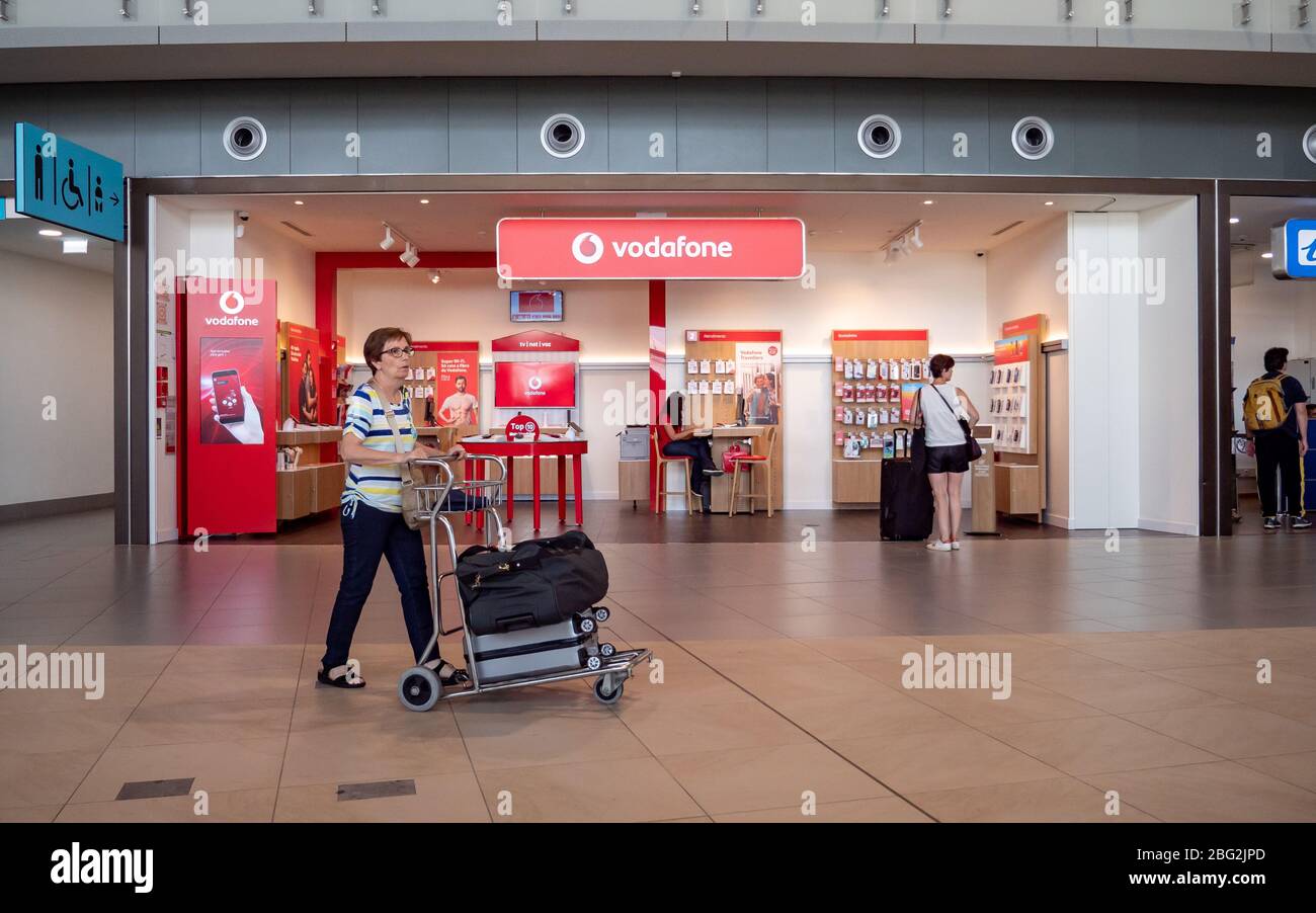 Vodafone Store. Eine reife weibliche Touristin geht durch den Vodafone Markenladen in der Abflughalle des Faro International Airport, Portugal. Stockfoto