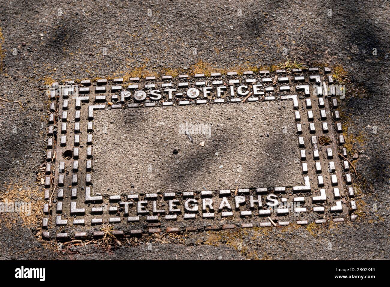 Post Office Telegraphen Zugangsabdeckung in Southend on Sea, Essex, Großbritannien. Alte, abgenutzte Wartungszugangsplatte mit Profilprofil und Moos Stockfoto