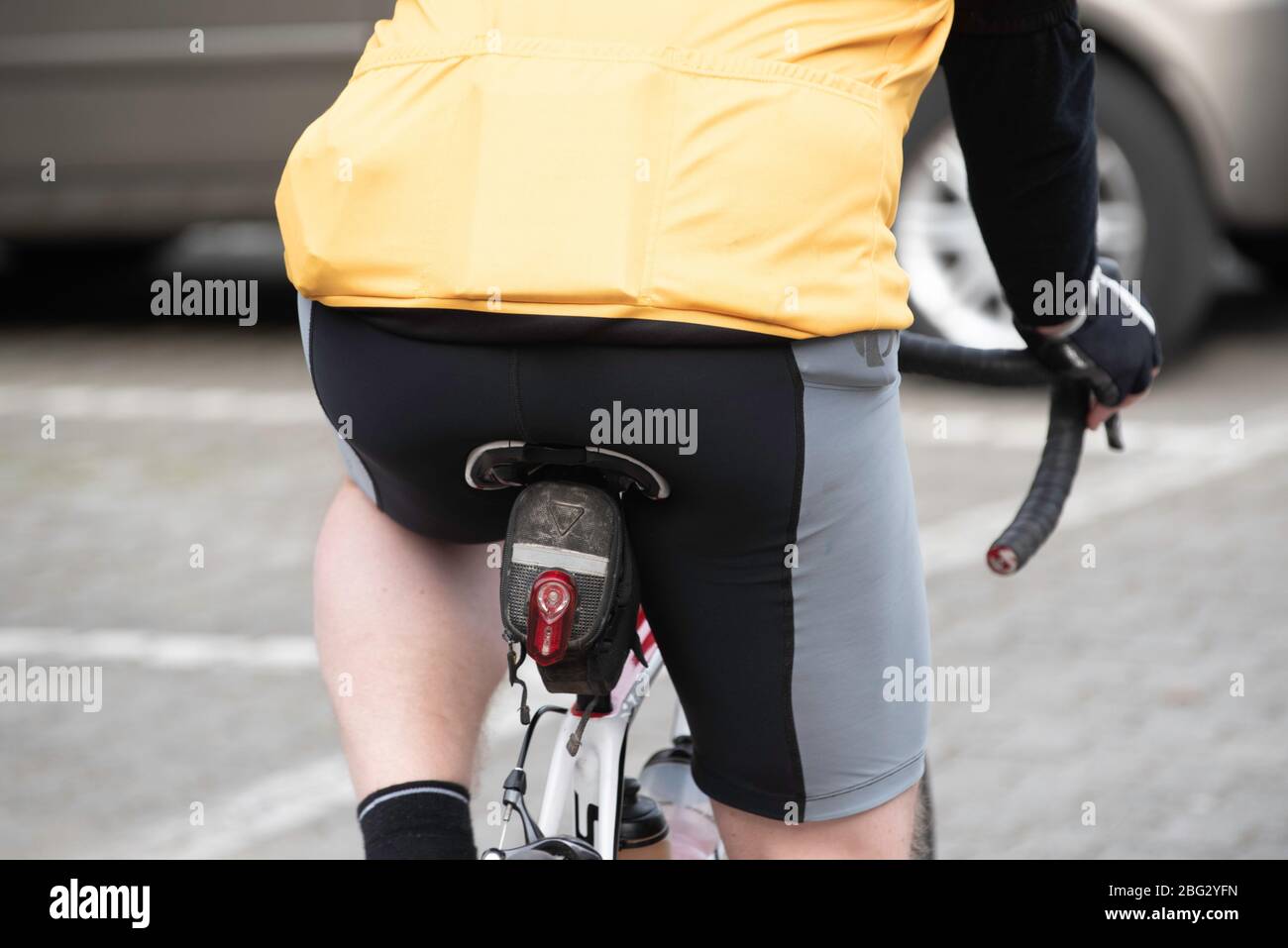 Ein großer, mit Lycra bedeckter männlicher Unterteil auf einem Fahrradsattel Stockfoto
