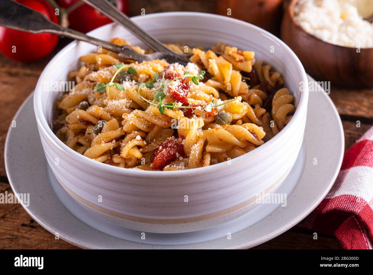 Eine Schüssel mit köstlichen Pasta puttanesca mit Rotini, Sardellen, schwarzen Oliven, Tomaten und Kapern. Stockfoto