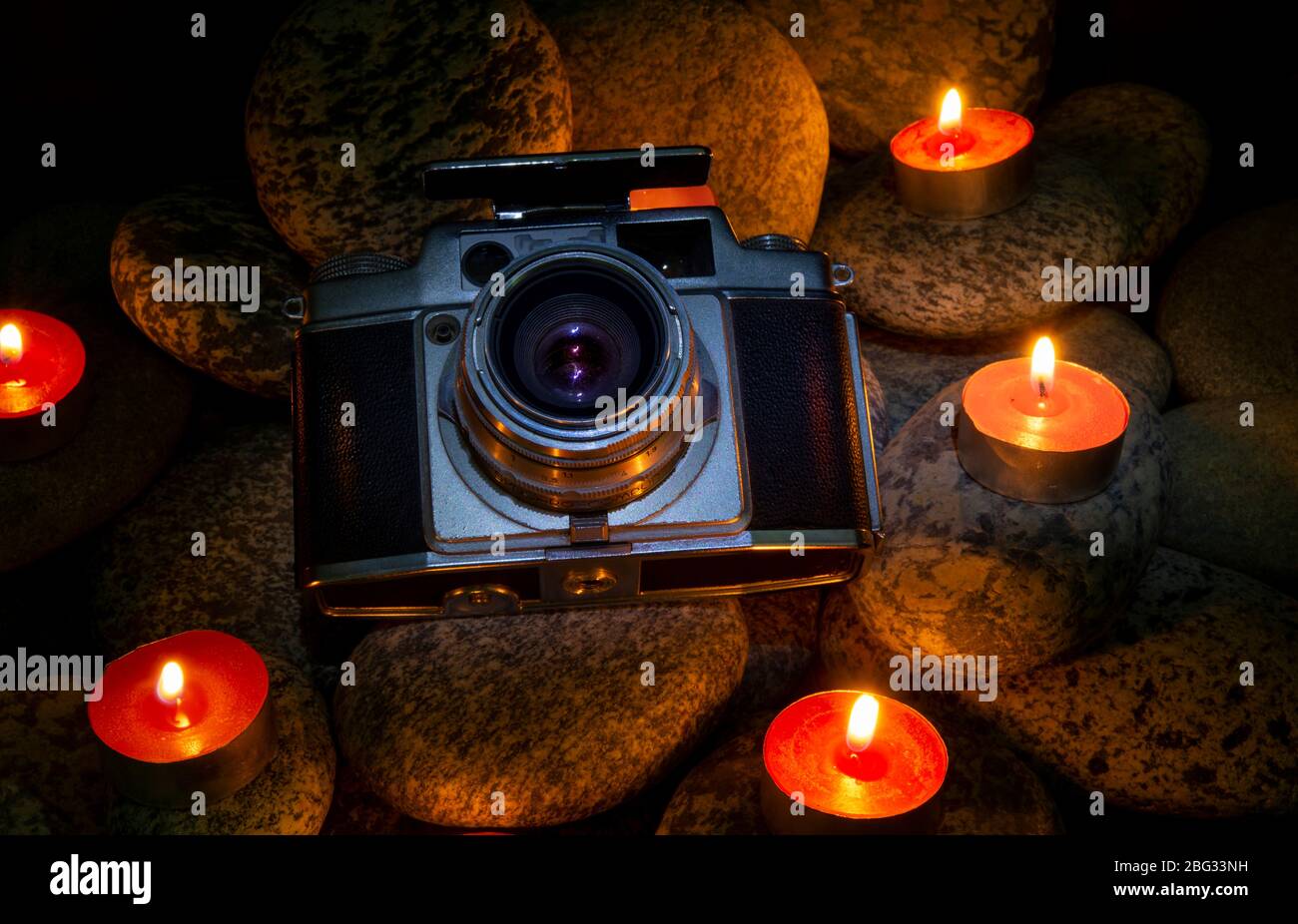 Vintage Kamera zwischen brennenden Kerzen auf Steinen platziert - nostelgic Thema Stockfoto