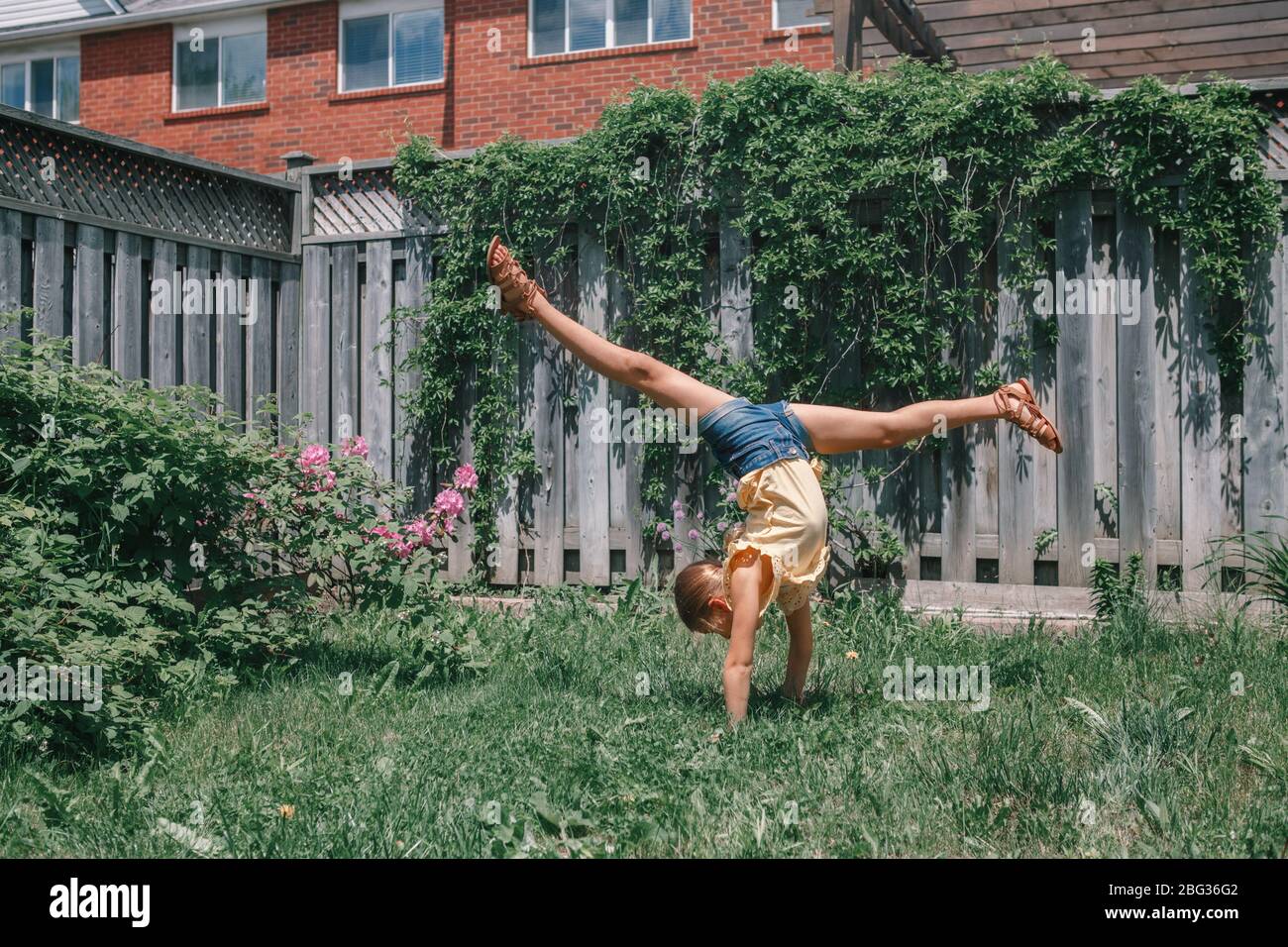 Lustige Kind Teenager-Mädchen tun cartwheel auf den Kopf stehen. Aufgeregt fröhlich Kind spielen im Freien. Happy Lifestyle Kindheit und Freiheit Geist. Stockfoto