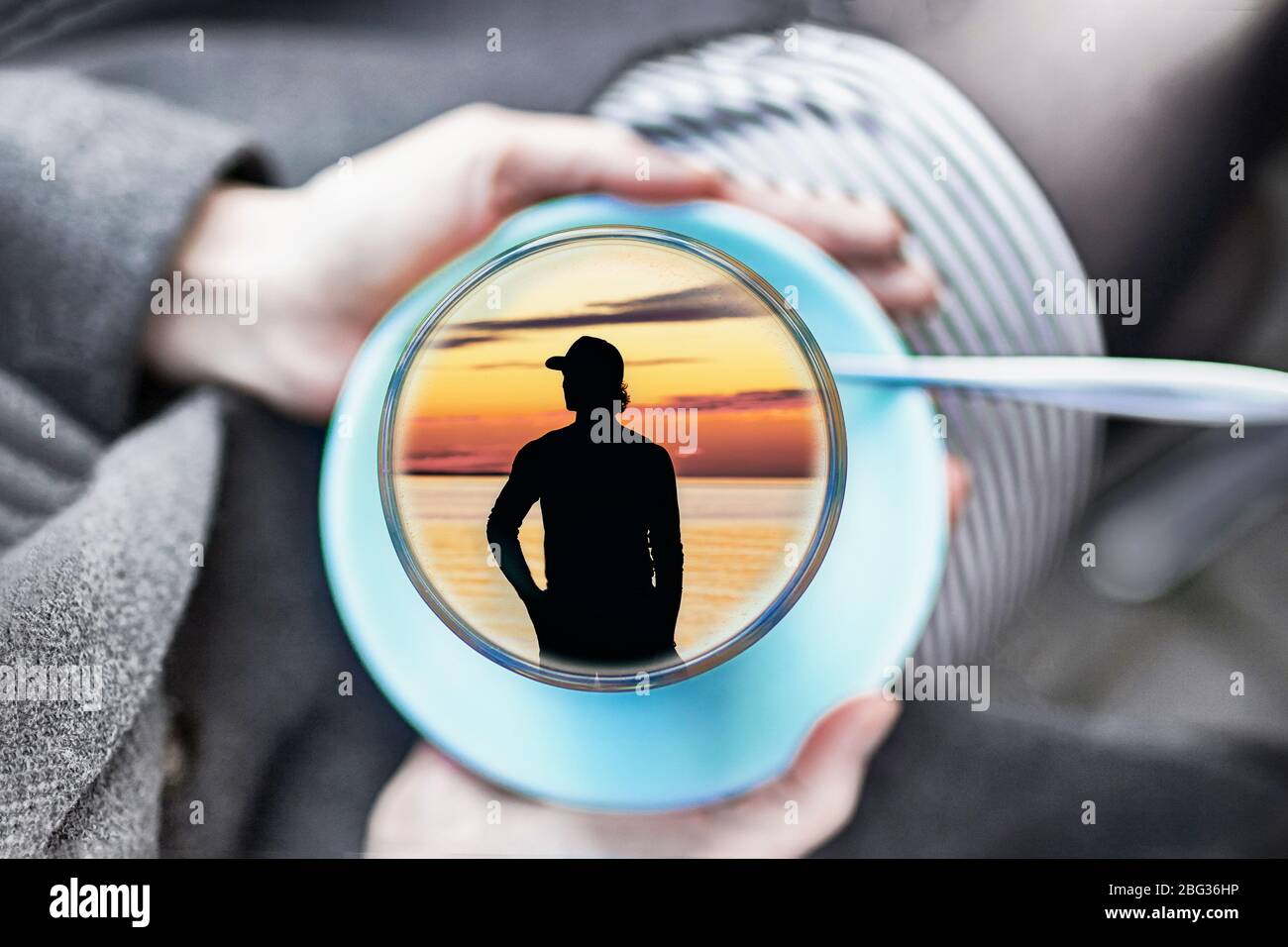 Weibliche Hände halten eine Tasse mit jungen Mann innen. Konzept süße Träume. Grauer Tag, bunte Träume Stockfoto