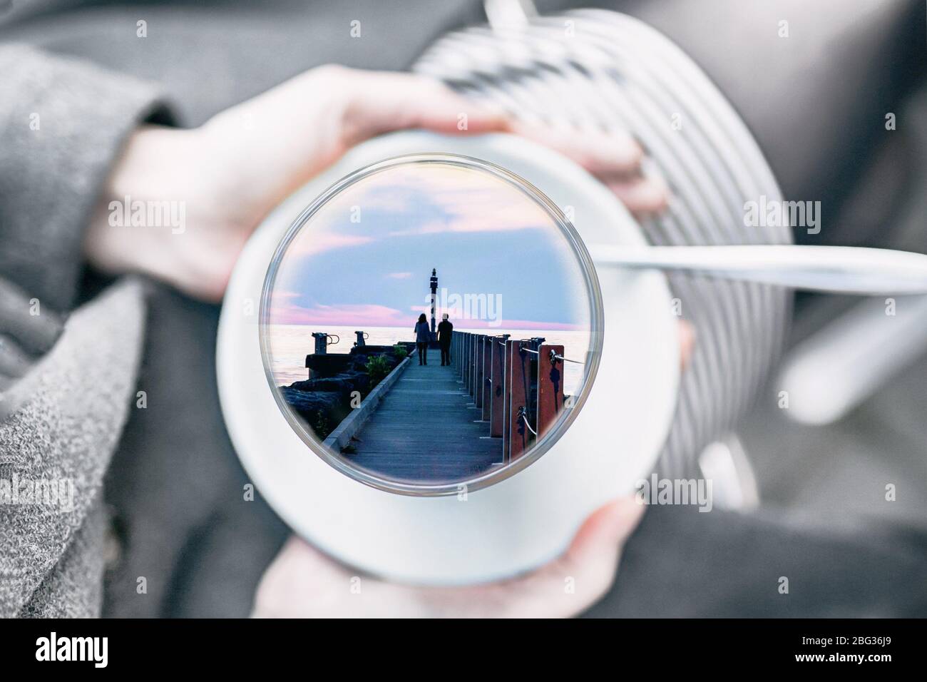 Weibliche Hände halten eine Tasse mit Paar innen. Konzept süße Träume. Grauer Tag, bunte Liebe Träume Stockfoto