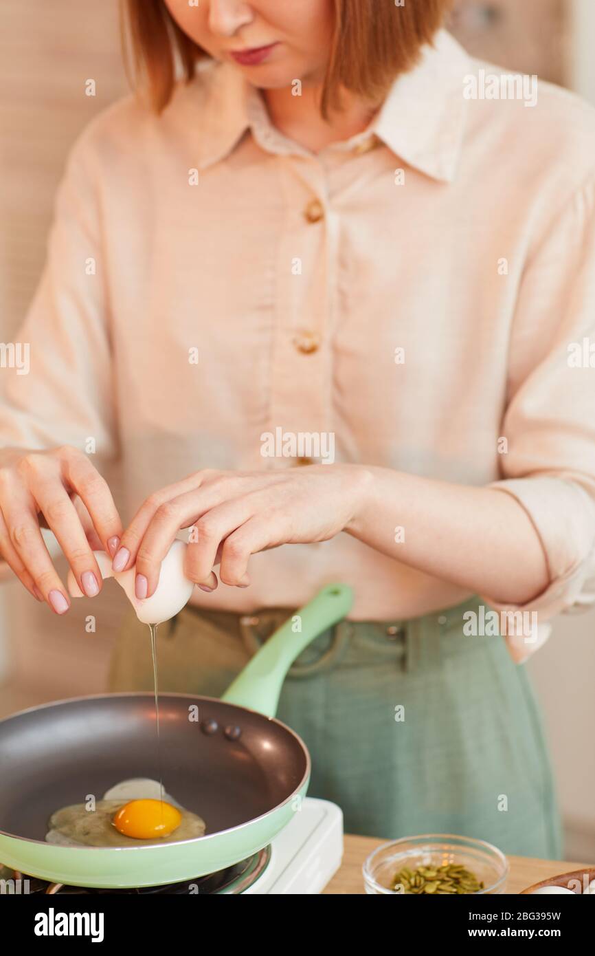 Vertikale Mitte Abschnitt Porträt der modernen jungen Frau Eier brechen beim Kochen gesundes Frühstück in der Küche Innenraum Stockfoto