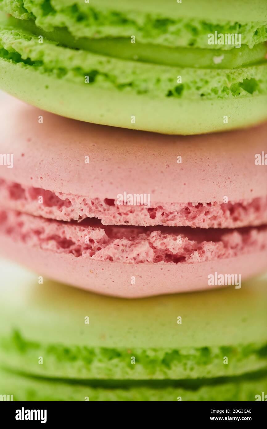 Vertikale Makro-Aufnahme von köstlichen pastellfarbenen Makronen in Reihe auf weißem Hintergrund gestapelt, Hintergrund mit Kopierraum Stockfoto