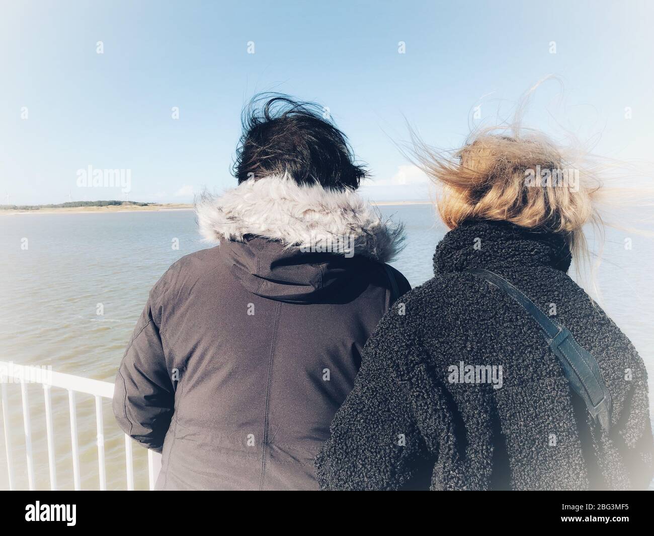 Zwei windgepeitschte Frauen stehen auf einem Boot und schauen auf die Küste, Fanoe, Jütland, Dänemark Stockfoto