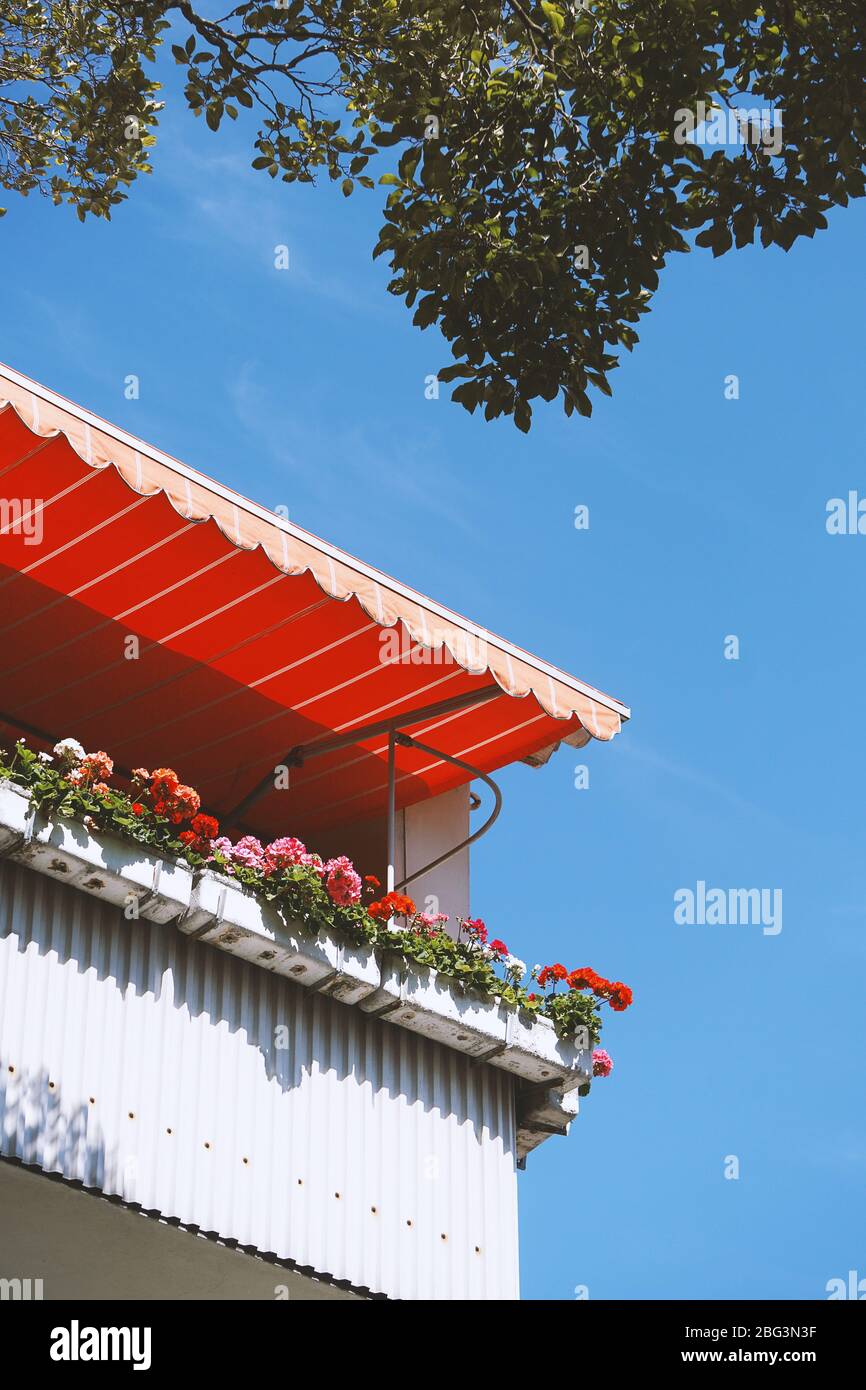 Balkon in deutschland mit Geranienblumen-Boxen und Markise oder Markise - zu Hause bleiben oder bleiben Konzept Stockfoto