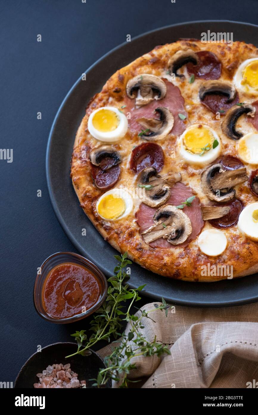 Nahaufnahme eines Eies, Pepperoni, Speck und Pilzpizza Stockfoto