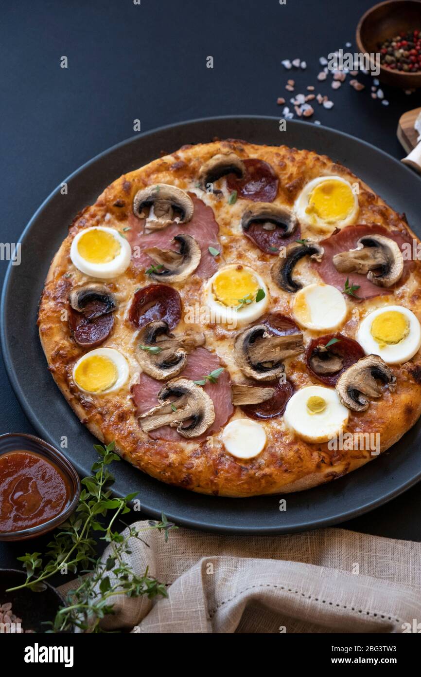 Nahaufnahme eines Eies, Pepperoni, Speck und Pilzpizza Stockfoto