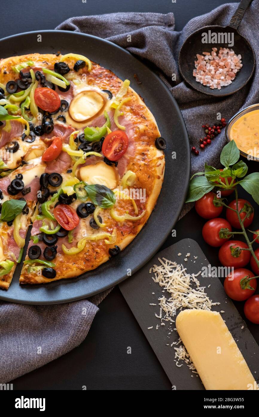 Nahaufnahme einer Pizza aus Schinken, Tomaten, Oliven, Paprika und Zwiebeln Stockfoto